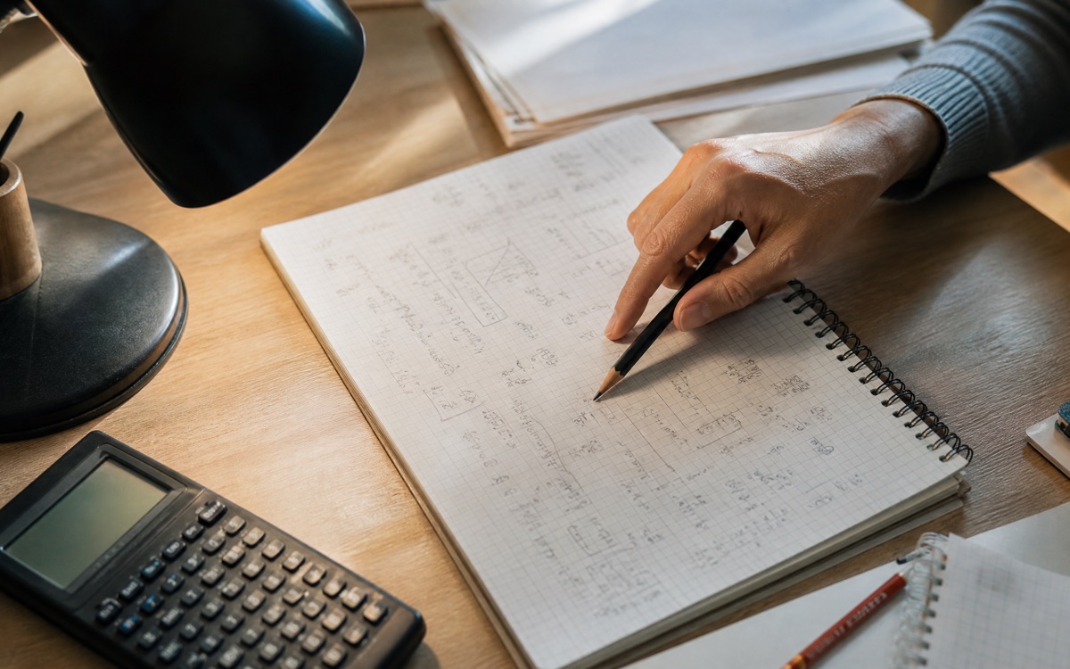El yazısı denklemlerle dolu matematik defteri, kalem ve hesap makinesi